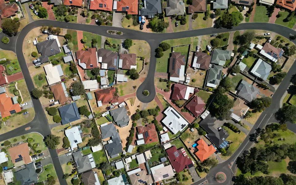 Aerial view of a suburban court with curving streets, tiled-roof houses, backyards and trees