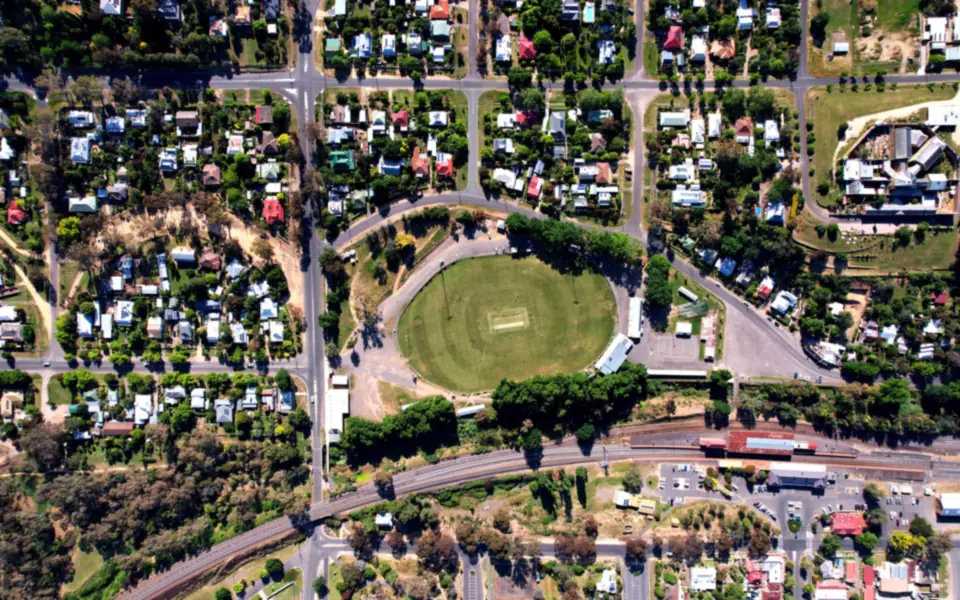 Straight-down aerial view of a country town's street grid, houses, sports oval and railway line