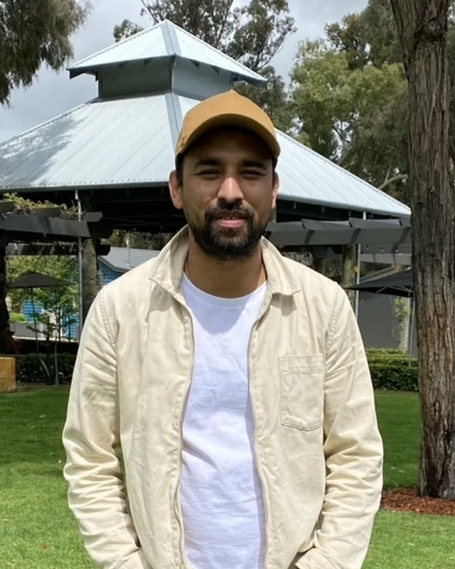 Ron Shrestha, founder and director of Ads Camps Digital Marketing, standing in a park in a tan cap